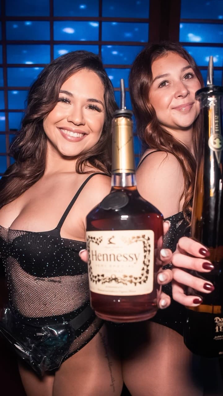 Ohm lounge staff members holding bottle of spirits